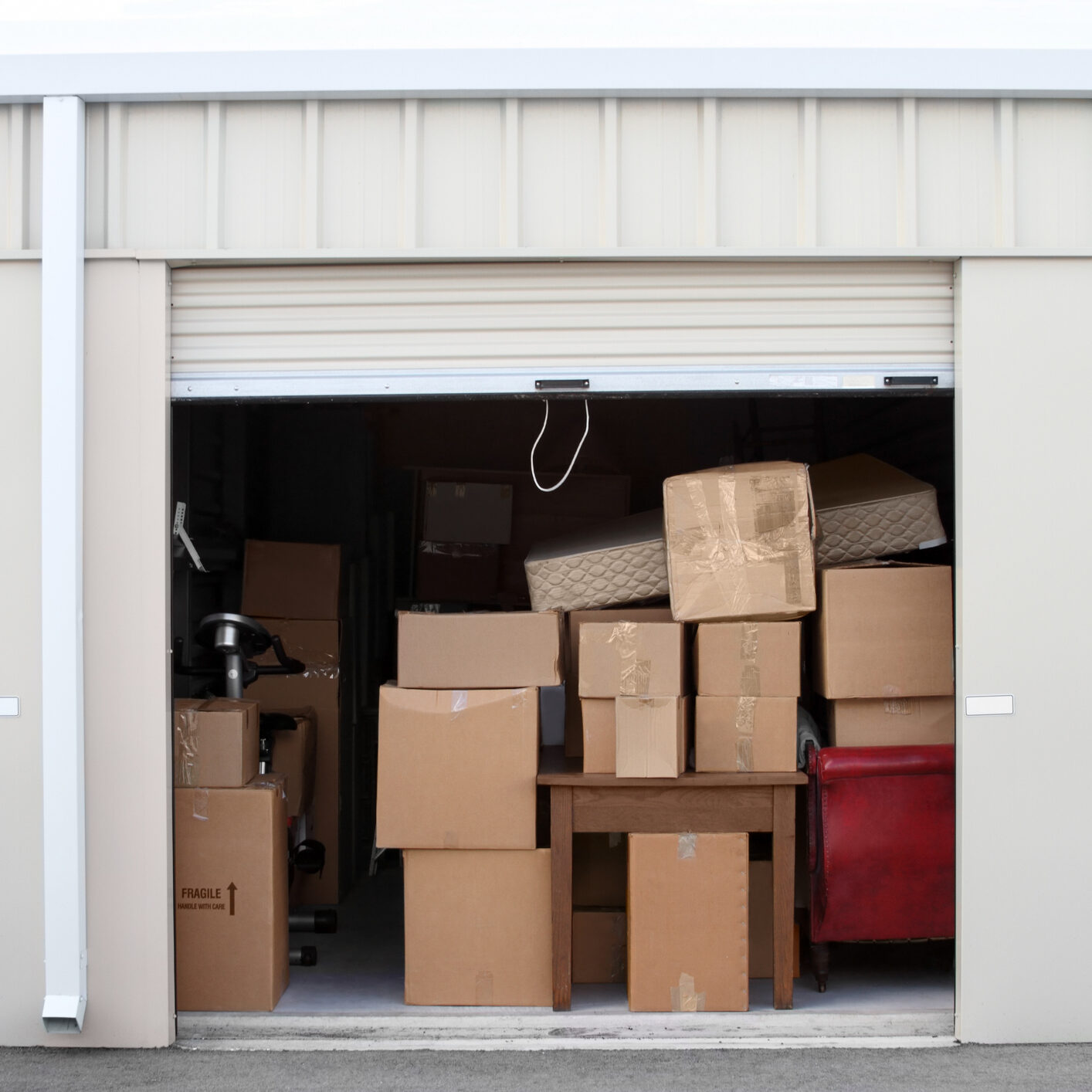 Warehouse building with self storage units. Self storage facility. Roll up doors on self storage facility. One door open with boxes and furniture in doorway.